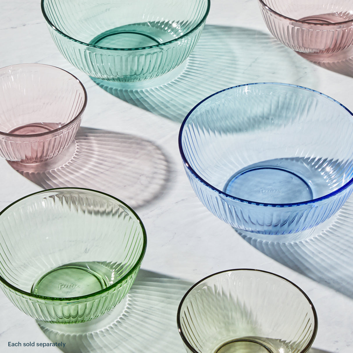 Set of colorful glass bowls on a light wooden surface