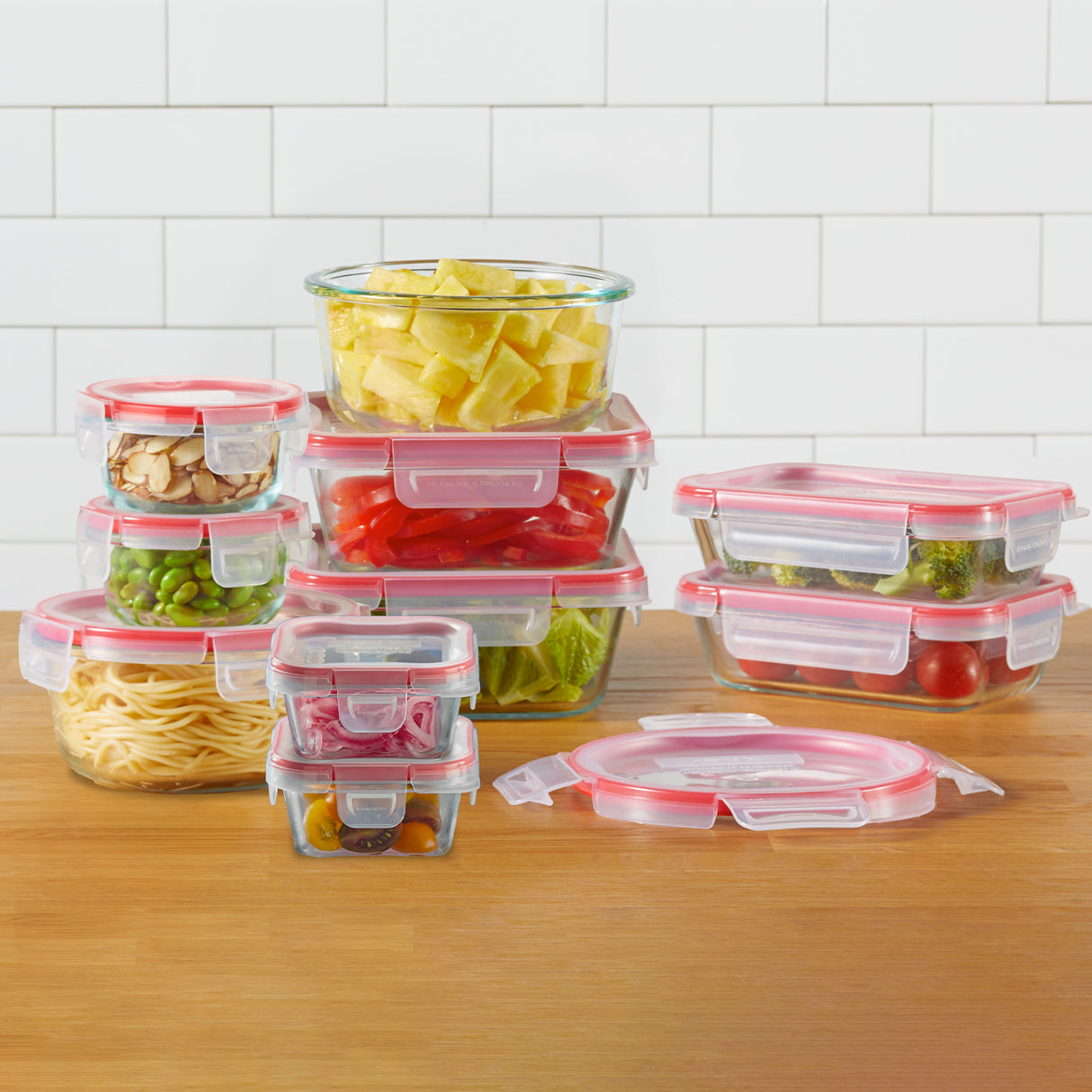 Set of clear food storage containers with red lids on a wooden surface.