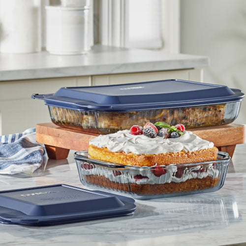 Glass bakeware with lemon chicken and layered berry cake on a table.
