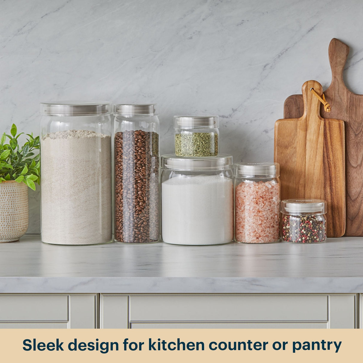 Glass jars with different contents on a kitchen counter with wooden cutting boards.