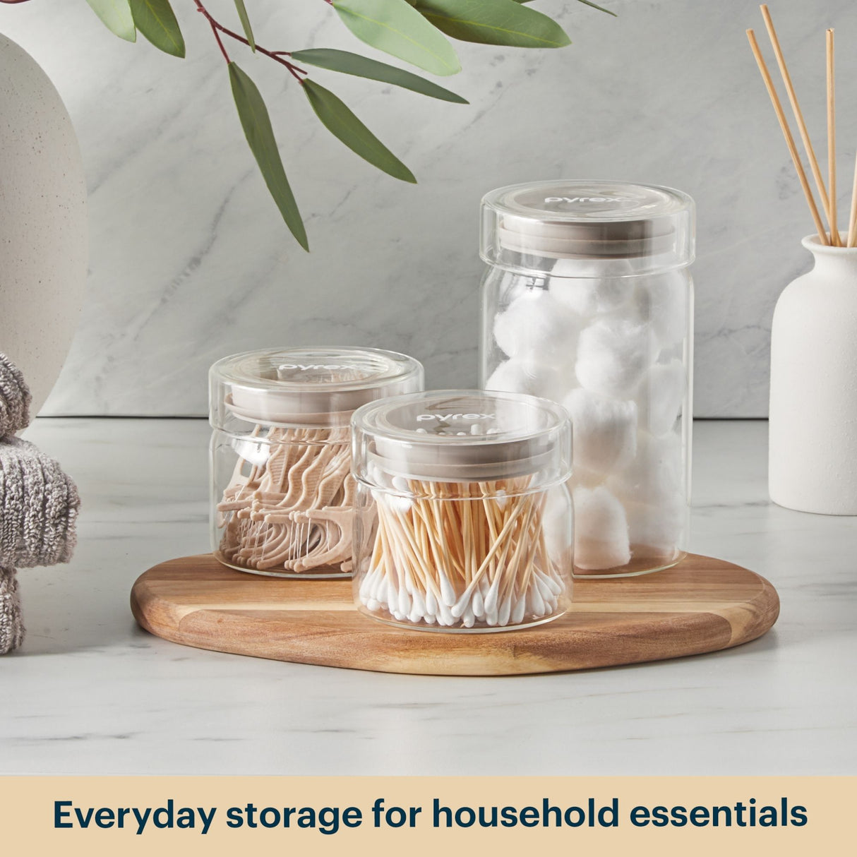 Clear jars with lids on a wooden tray against a light background