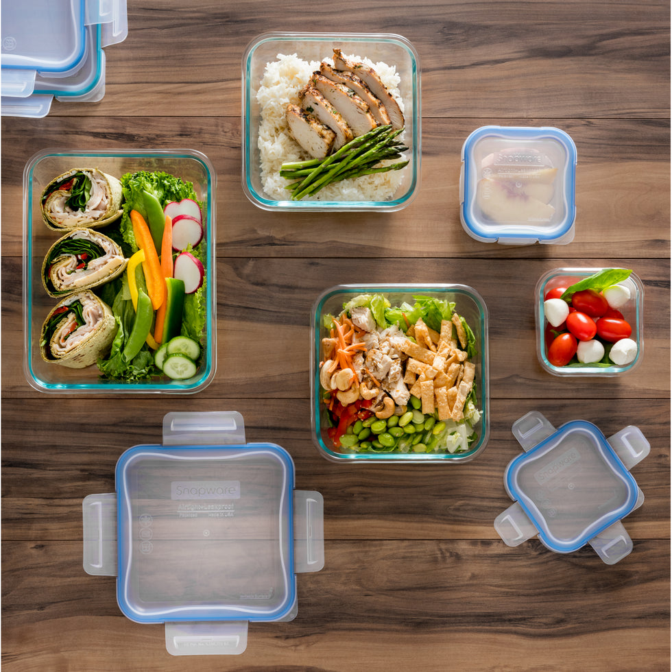 Glass meal prep containers with food  on a wooden table.