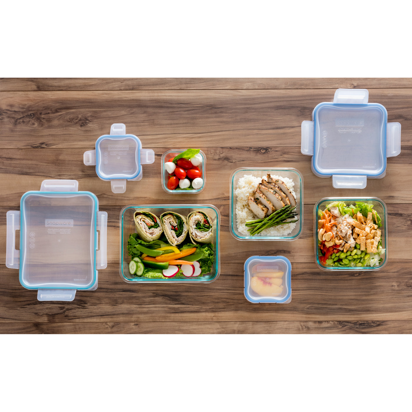 Glass meal prep containers with food  on a wooden table.