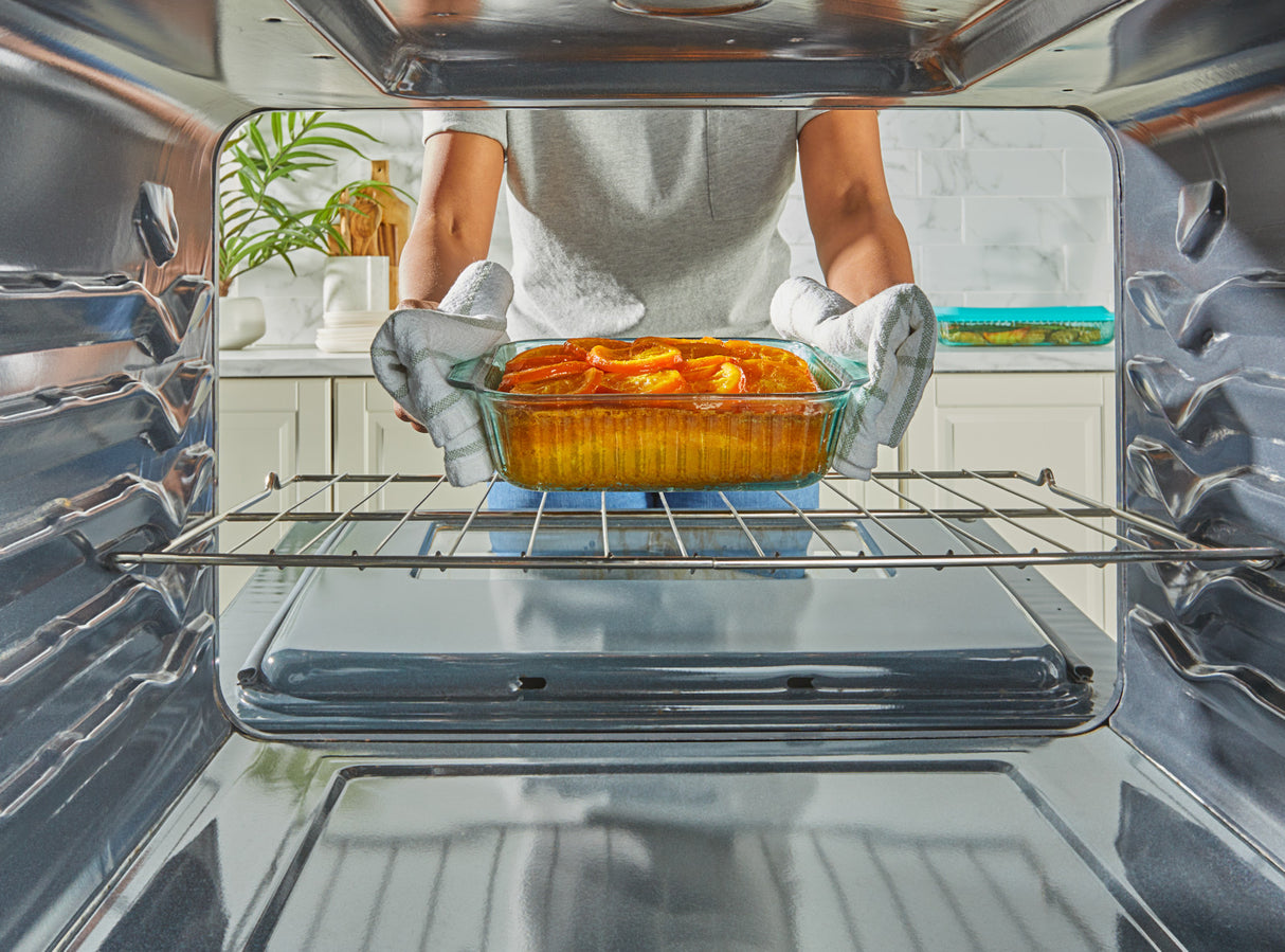 Person placing a dish of food into an open oven.