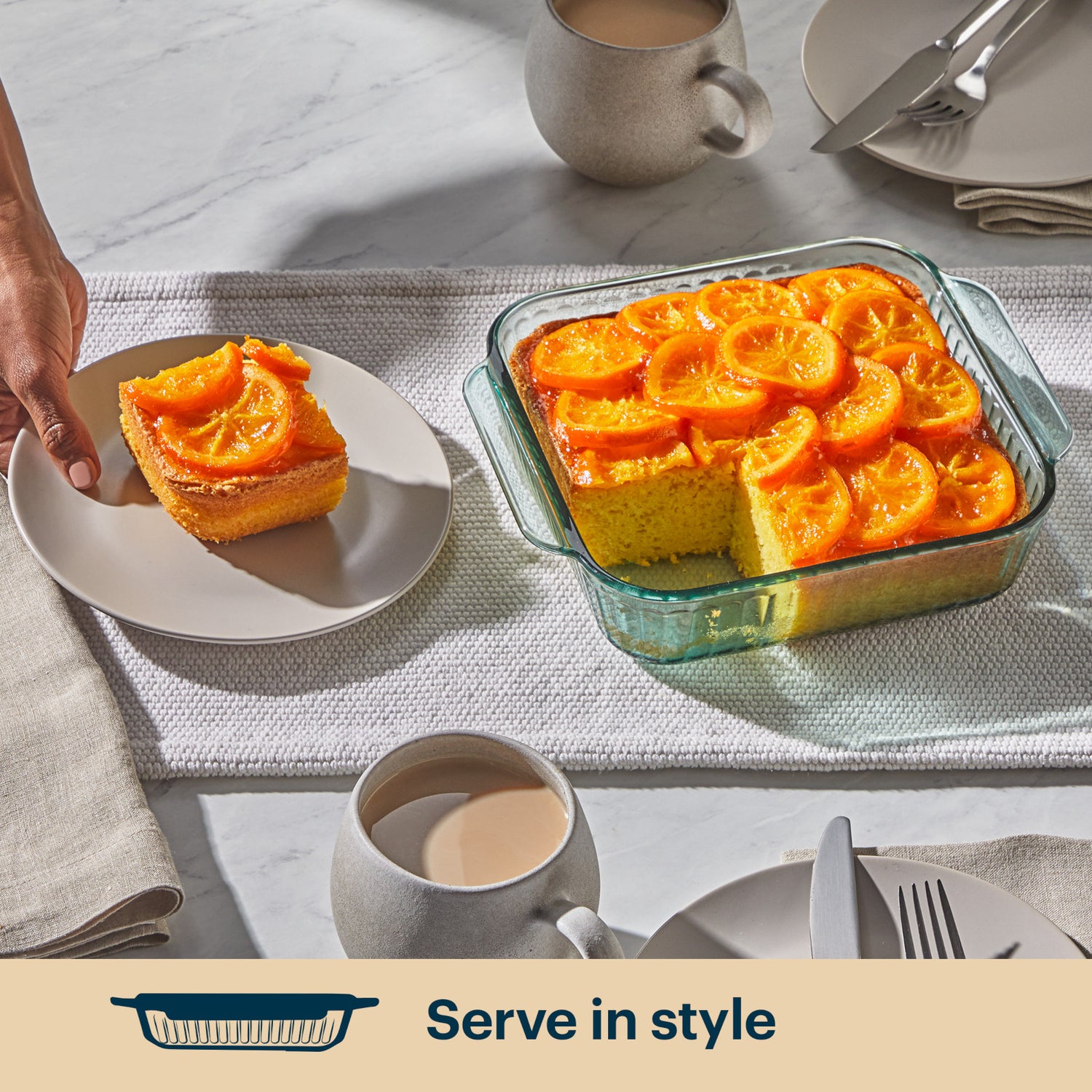 Baked dish with orange slices served on a plate with a cup of coffee, on a table setting.