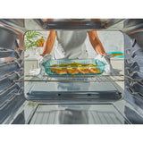 Person placing a dish into an open oven