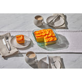 Table setting with a dish of orange cake and coffee cups on a marble surface