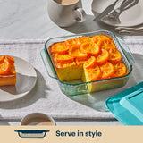 Glass dish with orange slices on a dessert, placed on a table with a cup and plates.