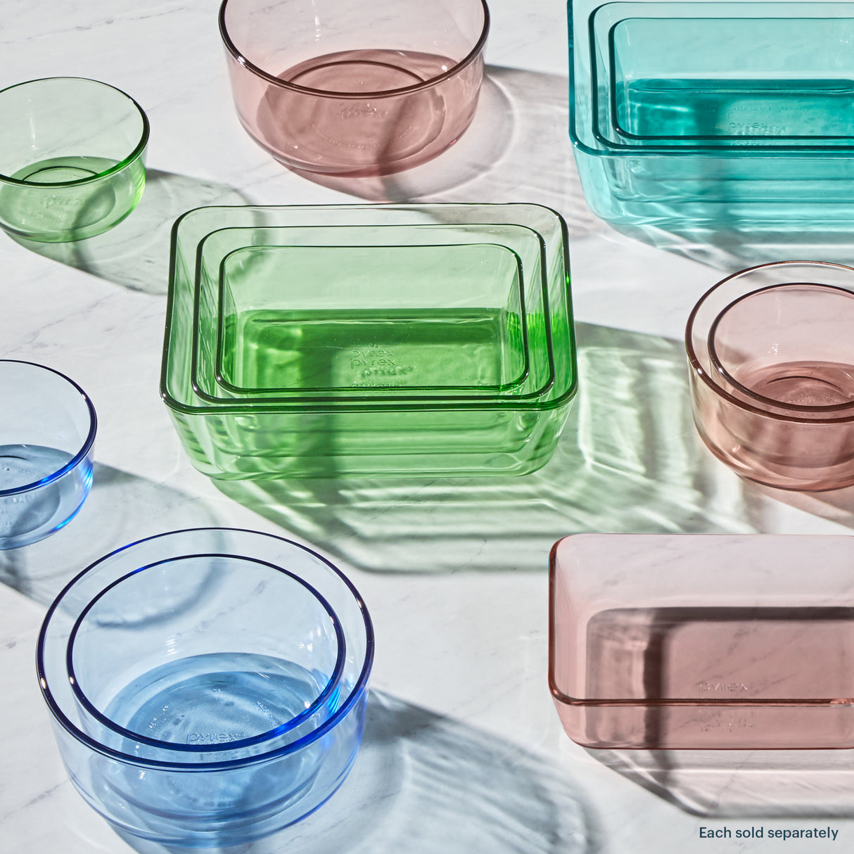 Colorful glass containers including bowls and a rectangular dish on a light surface.