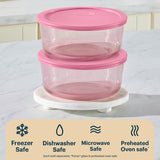 Two glass food containers with pink lids stacked on a white surface, with a label indicating safety features.