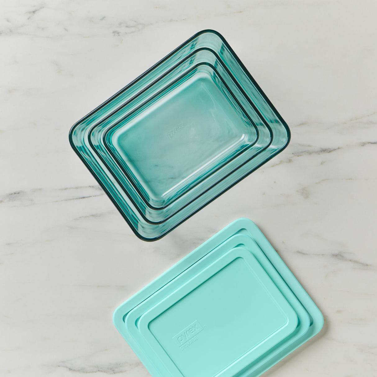 Set of three turquoise glass baking dishes on a marble surface