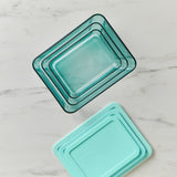 Set of three turquoise glass baking dishes on a marble surface