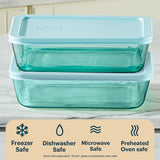 Two glass food storage containers with blue lids on a kitchen counter, featuring safety icons and text.