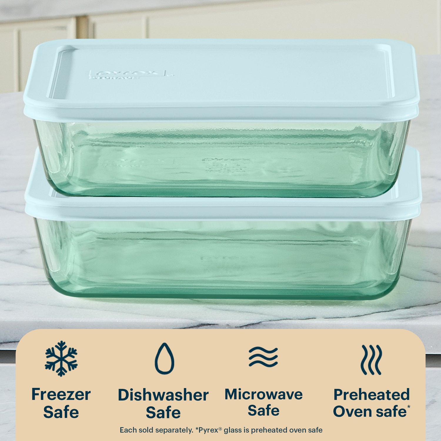 Two glass food storage containers with lids on a kitchen counter, featuring Pyrex branding.