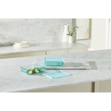 Glass food containers on a kitchen counter with a marble backsplash.