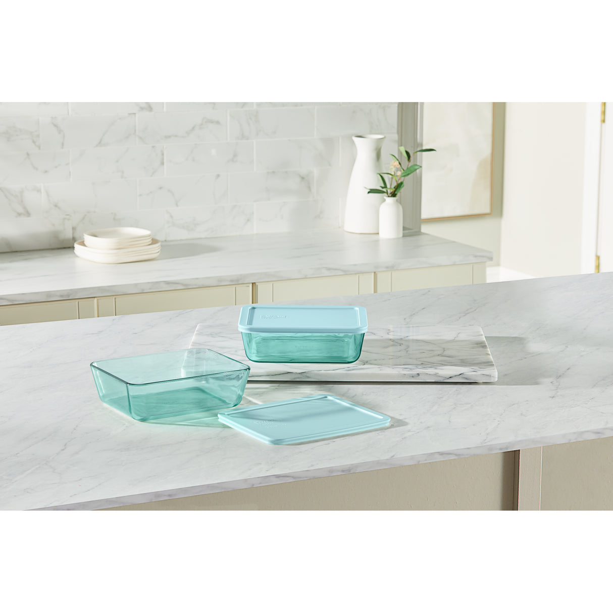 Set of teal glass containers on a marble countertop with a neutral background