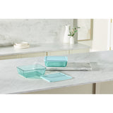 Set of teal glass containers on a marble countertop with a neutral background