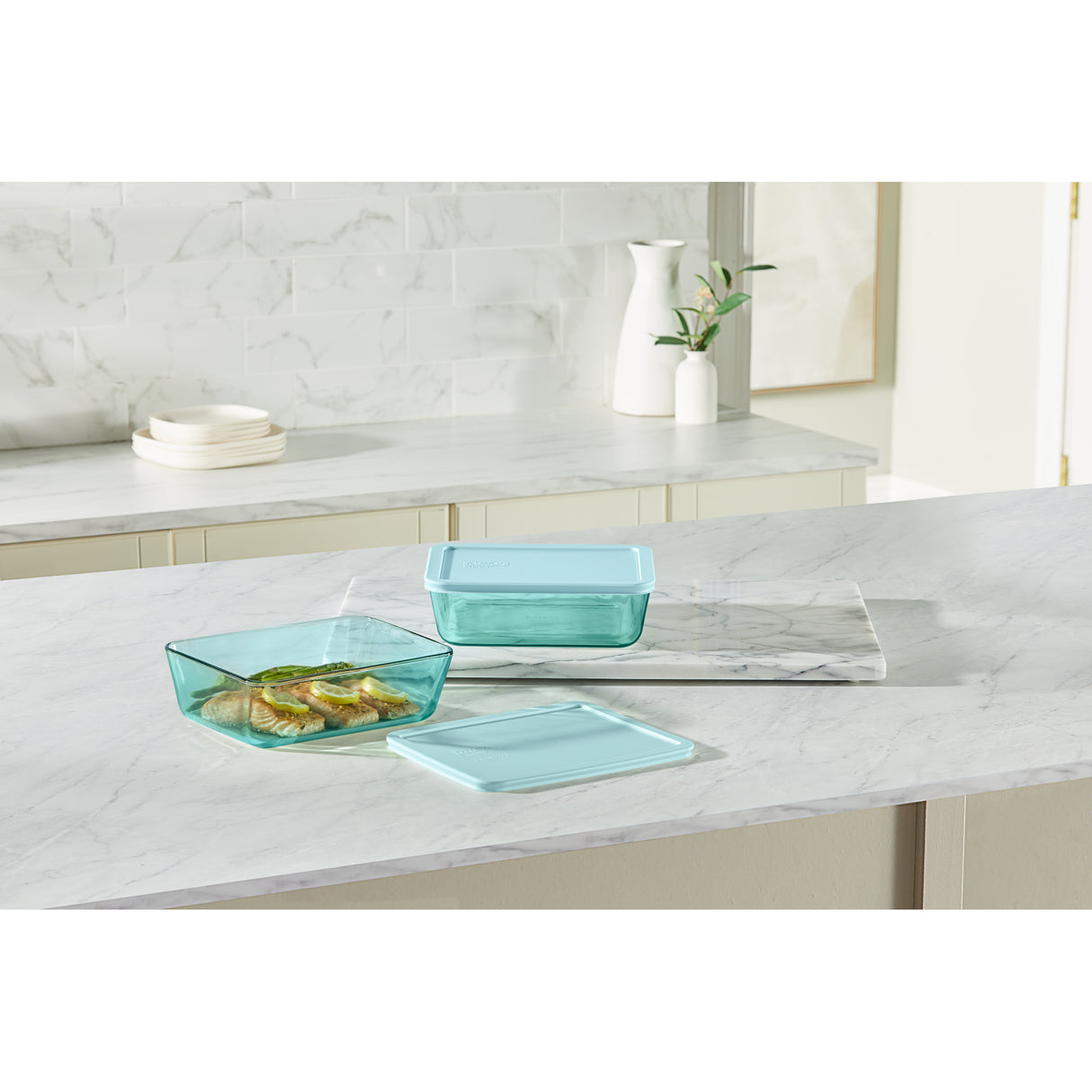 Set of teal glass containers on a marble countertop with a neutral background