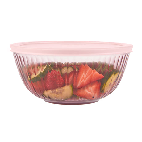 Clear glass bowl with pink lid containing sliced fruits on a white background
