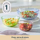 Three glass bowls filled with salad on a kitchen counter, with a brand logo in the corner.