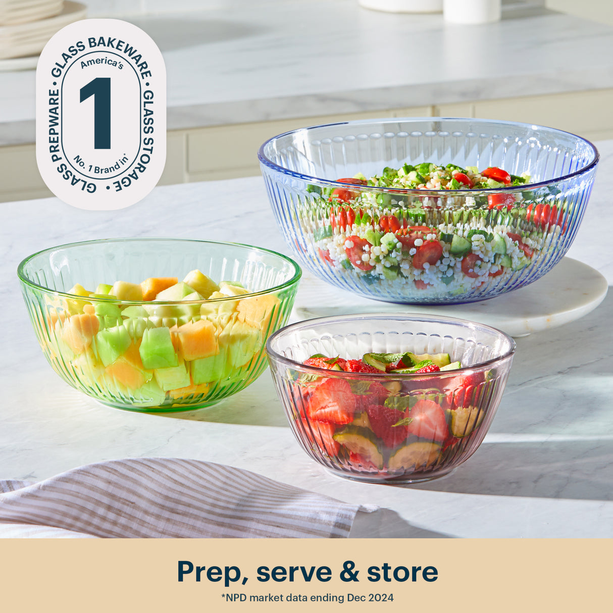 Three glass bowls filled with salad ingredients on a kitchen counter.