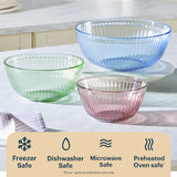 Three glass bowls in green, blue, and pink on a kitchen counter with safety icons below.