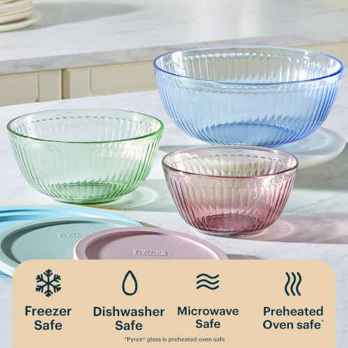 Set of colorful glass bowls on a kitchen counter with safety icons below.