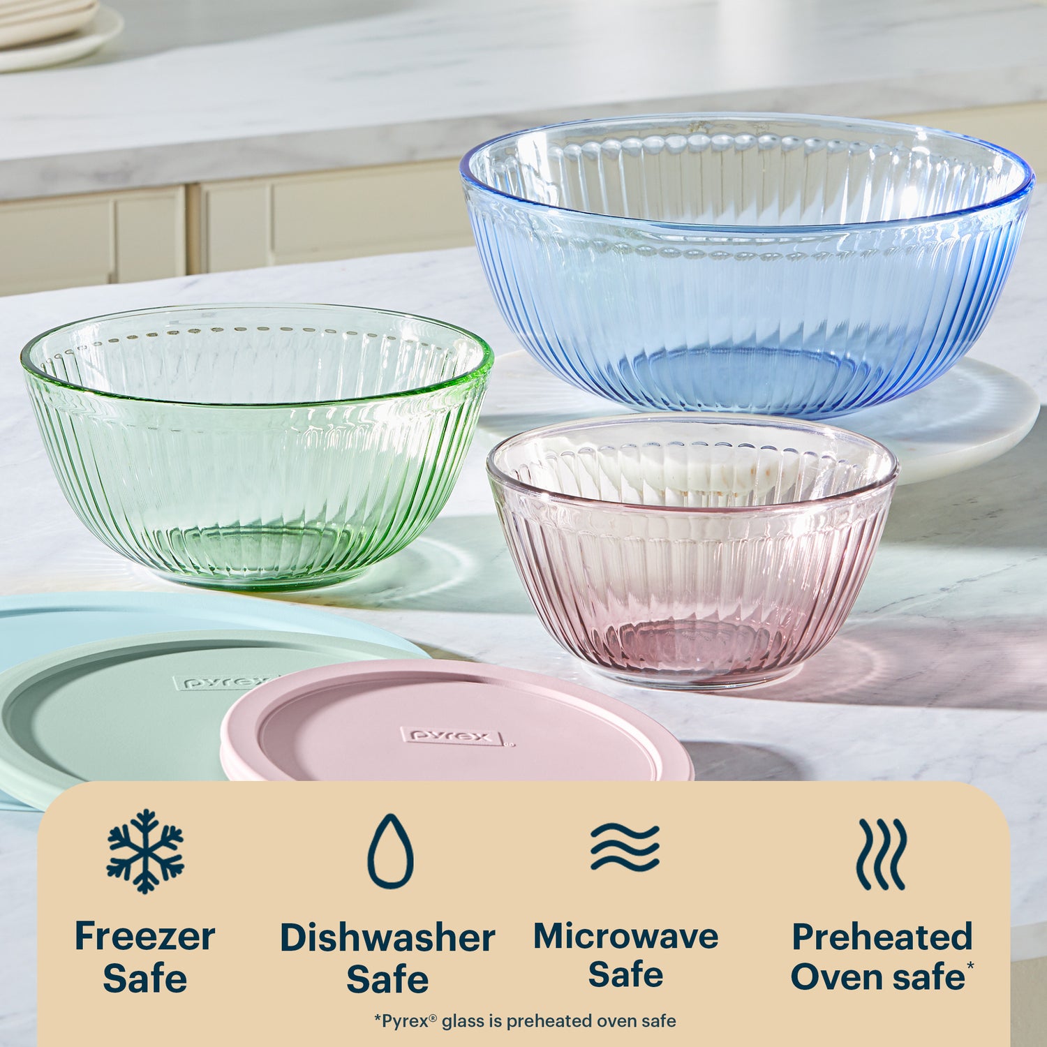 Set of three glass bowls in green, blue, and pink on a kitchen counter with Pyrex branding.