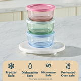 Stack of glass food containers with colored lids on a marble surface, featuring safety icons below.
