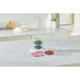 Set of colorful glass containers on a kitchen counter with a marble backsplash.