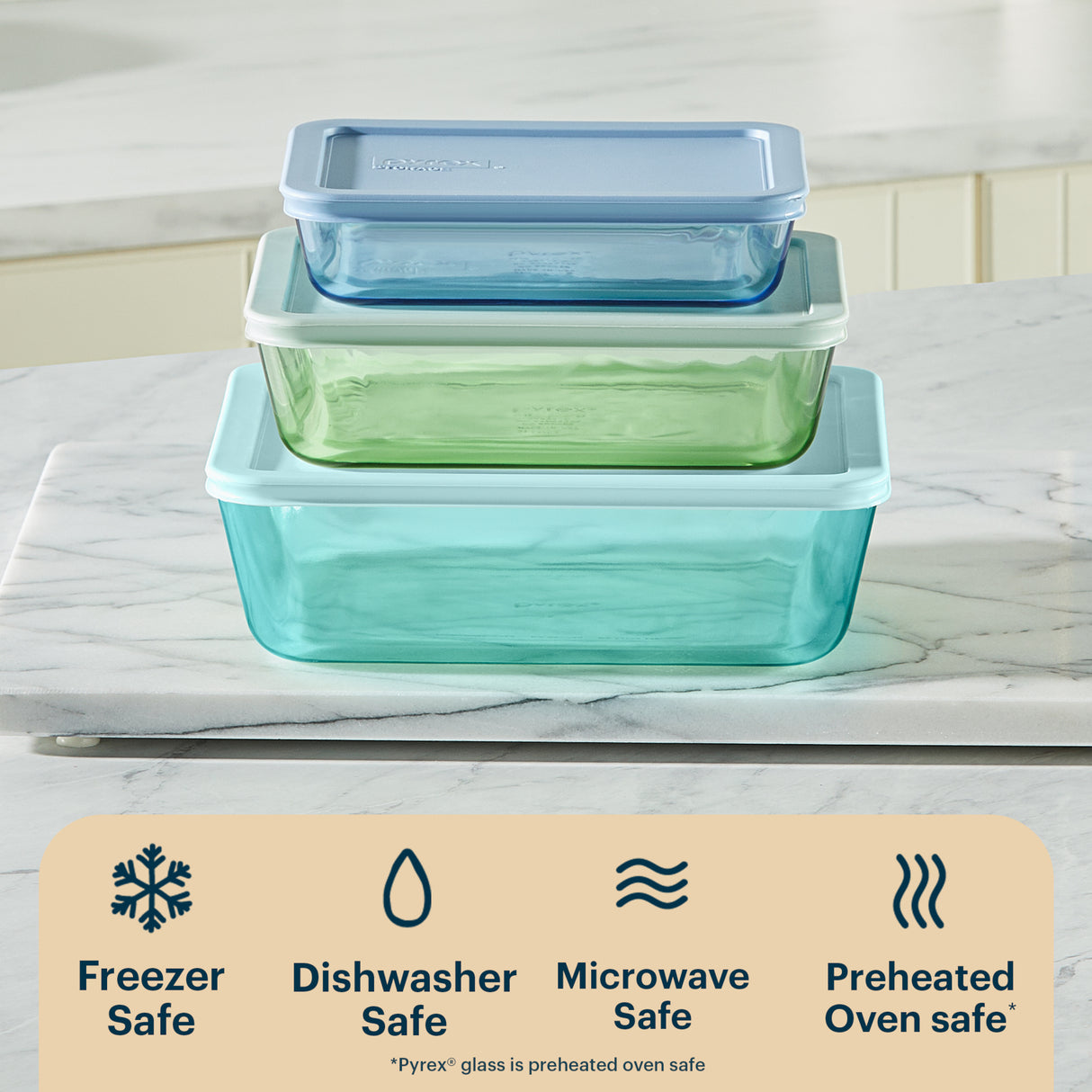 Set of glass food storage containers with lids on a marble surface, featuring Pyrex branding.