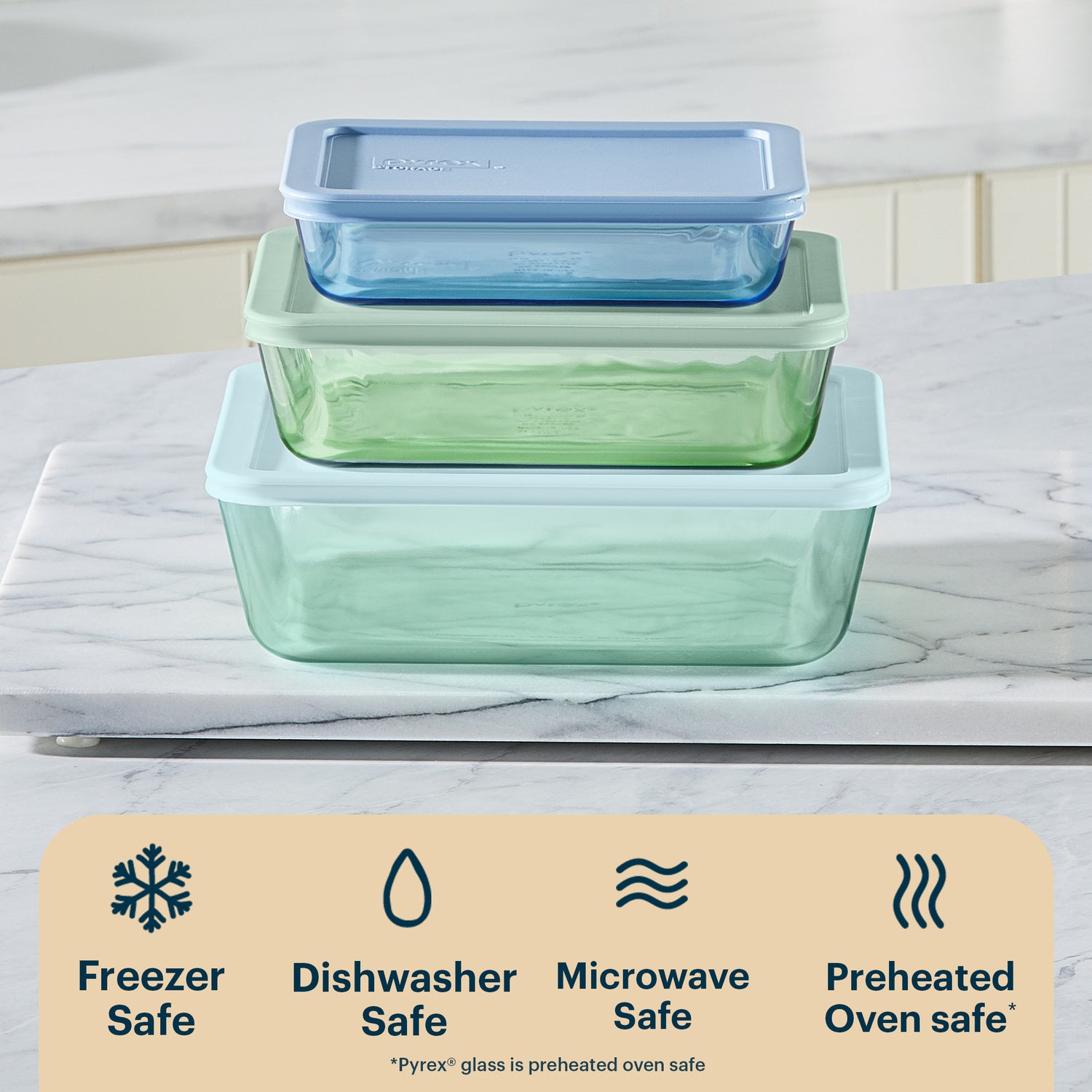 Set of glass food storage containers with blue and green lids on a marble surface, featuring Pyrex branding.