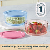 Glass bakeware set with pink and blue lids on a white surface, containing rice and strawberries.