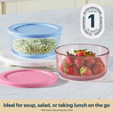 Glass food storage containers with lids containing rice and strawberries on a white surface.