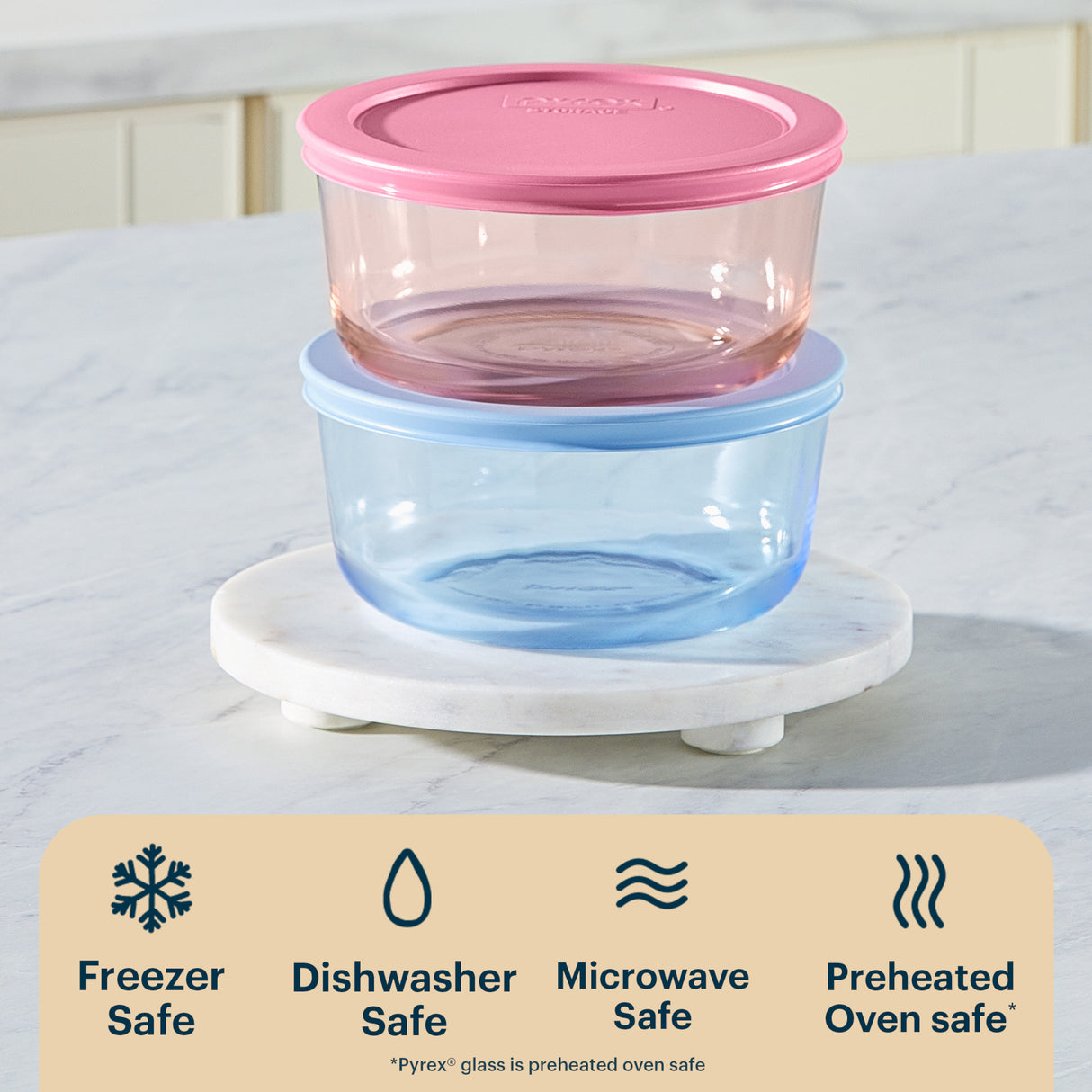 Set of two stacked food storage containers with pink and blue lids on a marble stand.