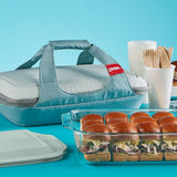 Pyrex baking dish with sandwiches and a carrying case on a blue background
