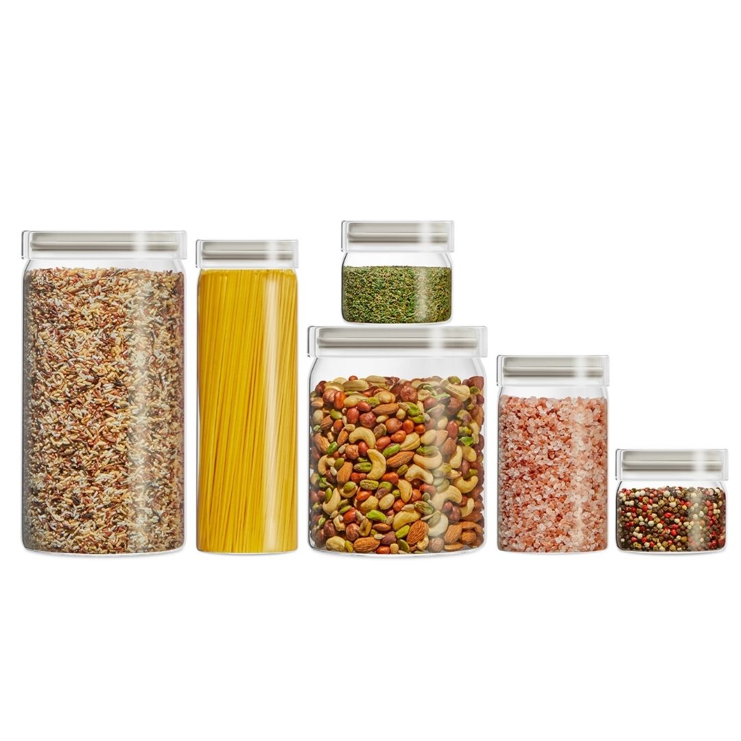 Set of glass storage jars with various foods inside on a white background