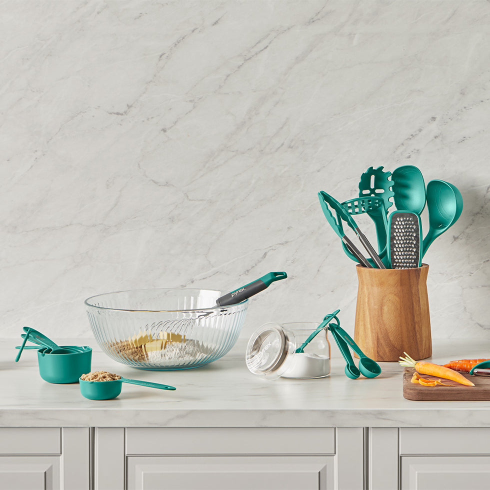 Teal kitchen utensils and measuring cups on a marble countertop