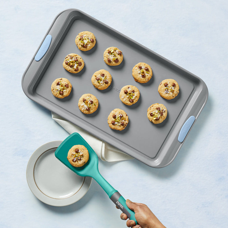 Baking tray with cookies and a spatula on a light blue background