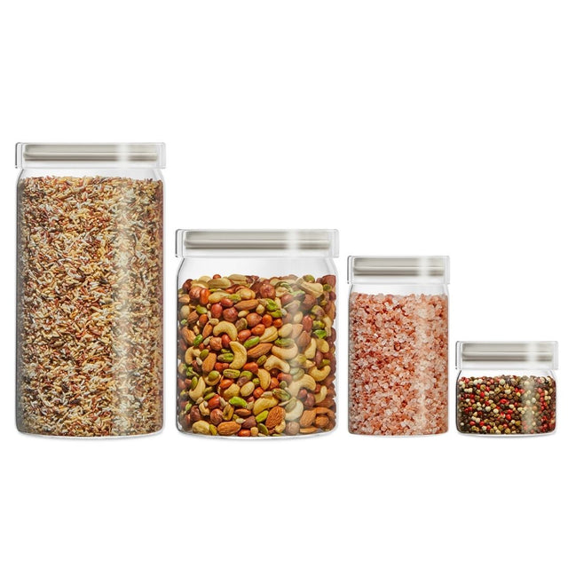 Set of four glass jars with lids, each containing different types of food on a white background