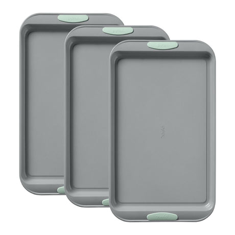 Three gray baking trays with green edges on a white background