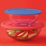 Stack of glass bowls with colorful fruit slices on a red background