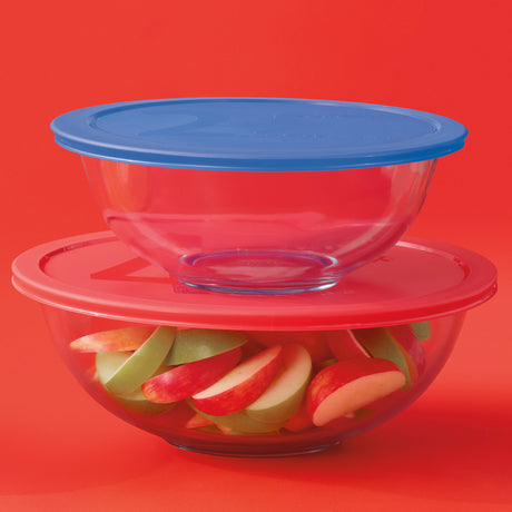 Stack of glass bowls with colorful fruit slices on a red background