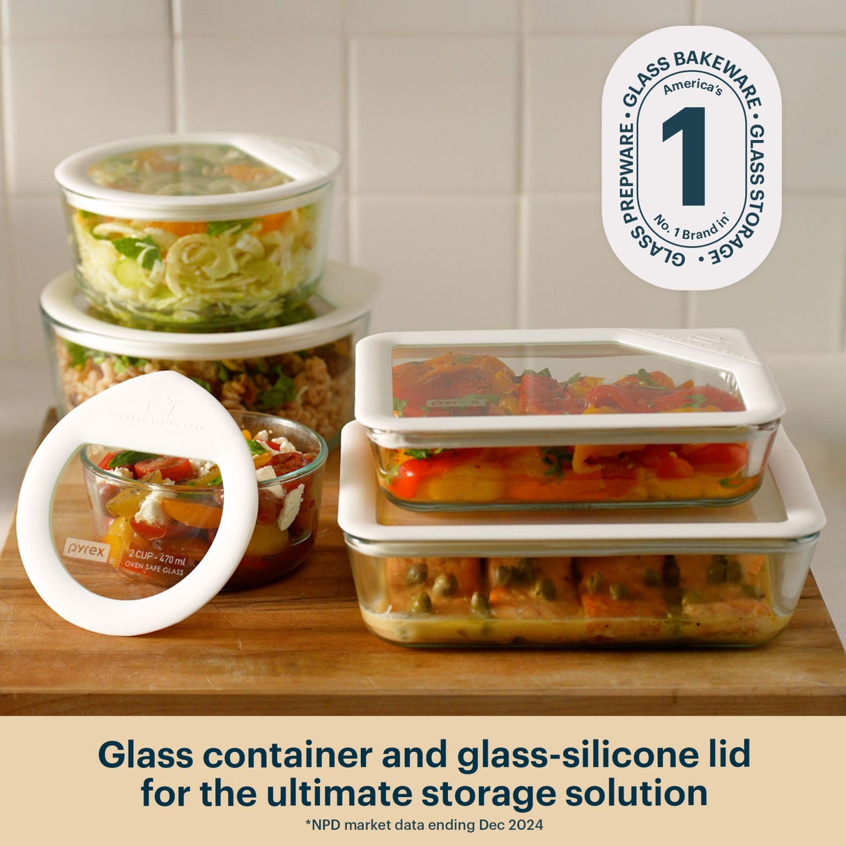 Pyrex glass food storage containers with white silicone clear  lids, filled with prepared meals, on a kitchen countertop.