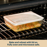 Pyrex glass container with a clear lid reheating food in an oven.