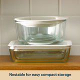 Stacked Pyrex glass storage containers with clear lids.