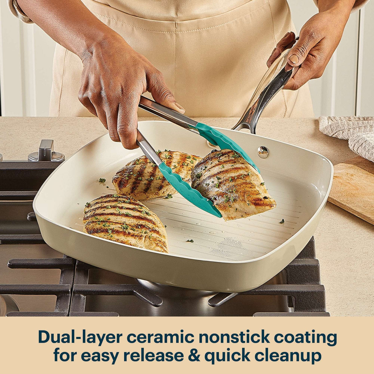 Person using a spatula to flip chicken in a ceramic nonstick frying pan on a stove.
