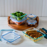 Glass food containers with lids on a wooden tray and white surface