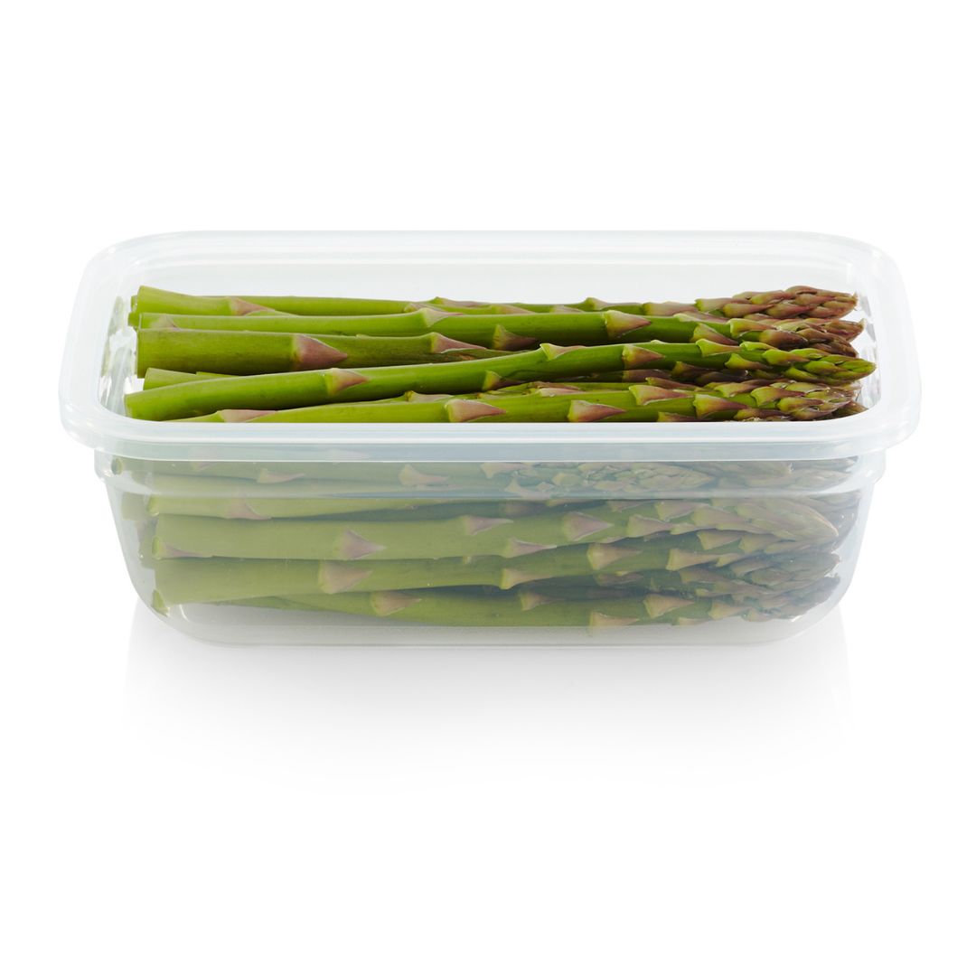 Green asparagus in a clear plastic container on a white background