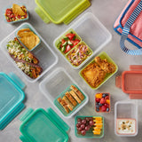 Assorted lunch containers with different food items on a gray surface